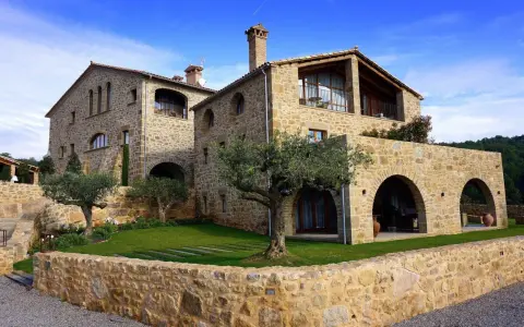 Magnifique maison en pierre calcaire avec des arches et un jardin verdoyant.