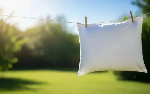 Un oreiller blanc sèche au soleil, suspendu à une corde à linge avec des pinces à linge. Un symbole de fraîcheur et de propreté après un bon nettoyer oreiller.