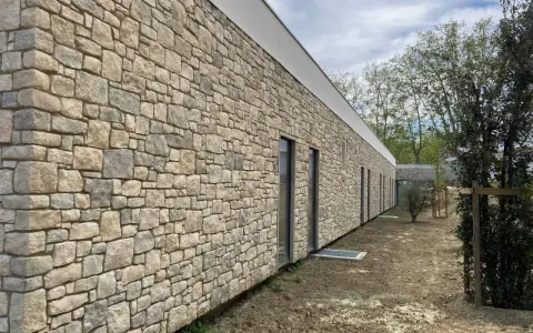 Façade d'un bâtiment moderne avec un revêtement en pierre calcaire construction, créant une esthétique naturelle et robuste.