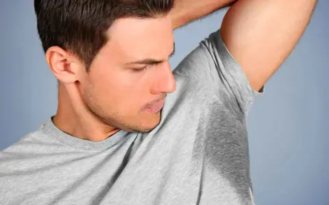 Un homme sent ses aisselles moites, cherchant comment enlever les taches sous les aisselles.