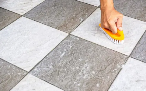 Main tenant utilise une brosse jaune pour faire briller le carrelage, révélant sa beauté naturelle.