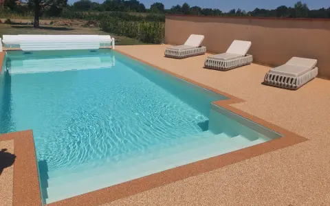 Piscine avec escalier, entourée de **pierre autour piscine** et de chaises longues.