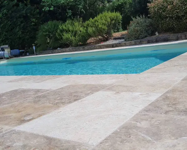 Le travertin autour de la piscine crée une terrasse naturelle et élégante, invitant à la détente sous le soleil.