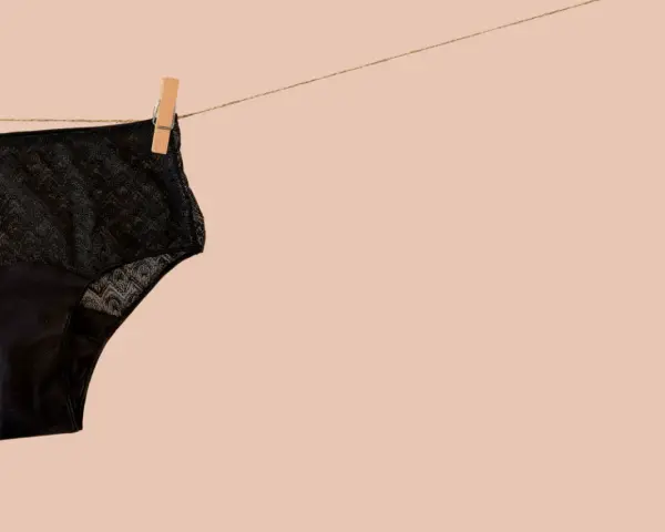 Culotte menstruelle noire en dentelle, suspendue sur une corde à linge. Apprenez comment laver culotte menstruelle pour une utilisation durable.