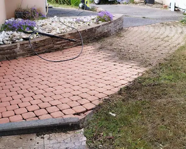 Un nettoyeur haute pression enlève les taches noires, lichen noir sur pierre. Le pavage est presque propre.