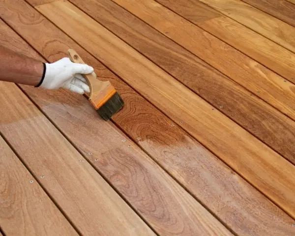 Application d'un produit protecteur sur un platelage en bois exotique, révélant sa beauté naturelle.