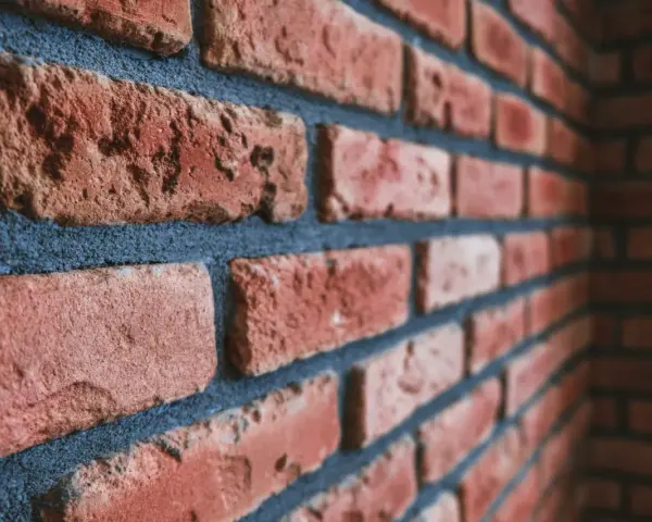 Gros plan sur un mur de briques rouges avec des joints bleus foncés. Idéal pour illustrer comment nettoyer des briques après avoir fait les joints.