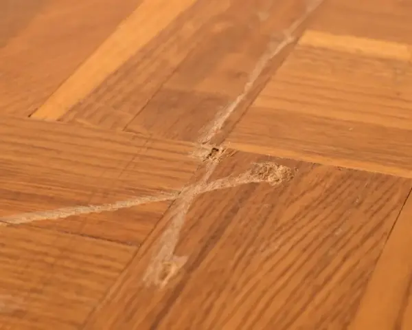 Parquet vitrifié abîmé par des frottements, montrant des marques et des éclats de bois. Comment enlever trace de frottement sur parquet vitrifié.