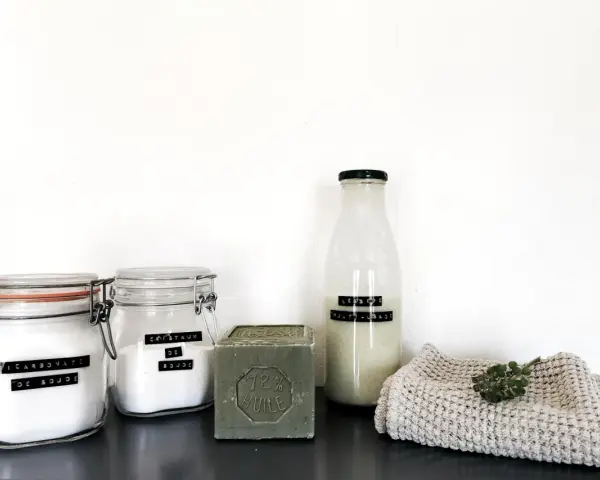 Ingrédients pour la meilleure recette lessive maison : bicarbonate de soude, cristaux de soude, savon de Marseille et une bouteille de lessive liquide.