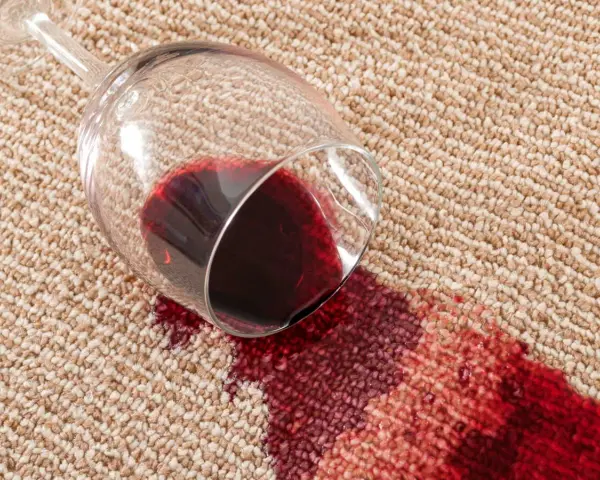 Verre de vin renversé sur la moquette, créant une tache rouge. Une astuce de grand-mère pour une tache de vin rouge serait utile ici.