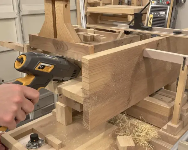 Un artisan utilise un outil pour enlever le saturateur bois d'une pièce de bois massif.