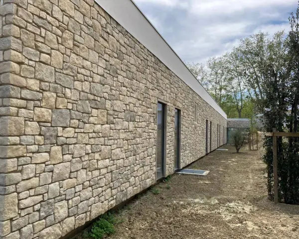 Façade d'un bâtiment moderne avec un revêtement en pierre calcaire construction, créant une esthétique naturelle et robuste.
