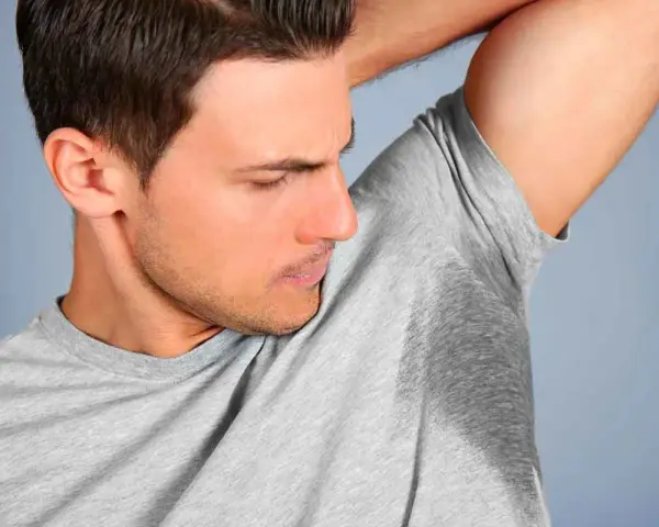 Un homme sent ses aisselles moites, cherchant comment enlever les taches sous les aisselles.
