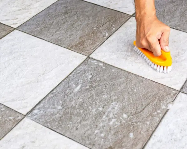 Main tenant utilise une brosse jaune pour faire briller le carrelage, révélant sa beauté naturelle.