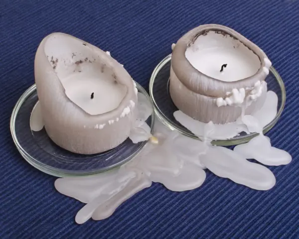 Deux bougies fondent, laissant une tache de bougie sur la pierre poreuse. La cire blanche coule sur les soucoupes en verre.