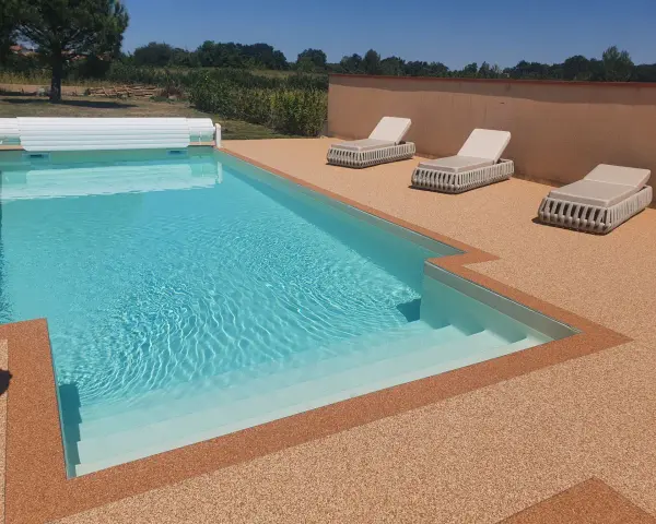 Piscine avec escalier, entourée de **pierre autour piscine** et de chaises longues.