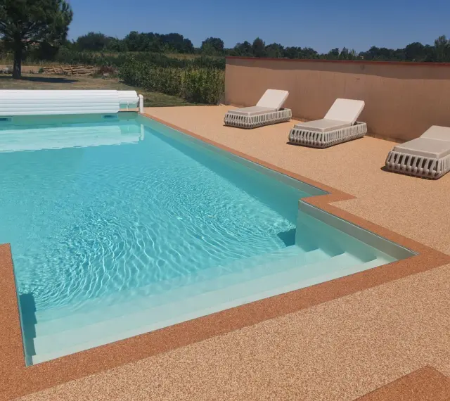 Piscine avec escalier, entourée de **pierre autour piscine** et de chaises longues.