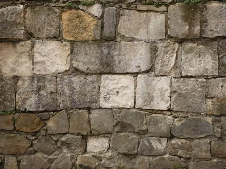 Mur en pierres naturelles, certaines semblant prêtes à décaper pour révéler leur éclat d'origine.