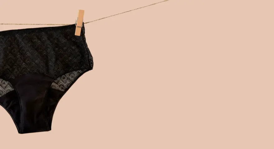 Culotte menstruelle noire en dentelle, suspendue sur une corde à linge. Apprenez comment laver culotte menstruelle pour une utilisation durable.