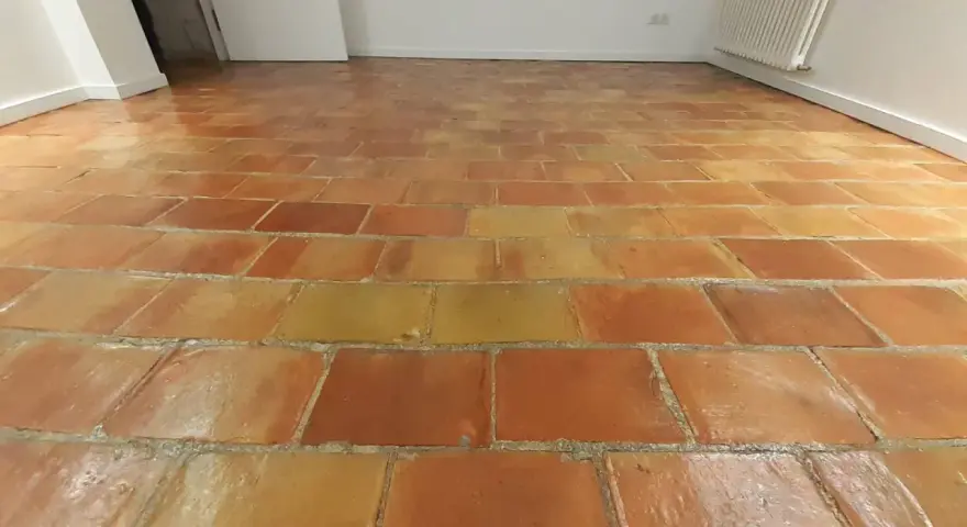 Sol en terre cuite aux tons chauds, avec un joint de barbotine visible entre les carreaux.