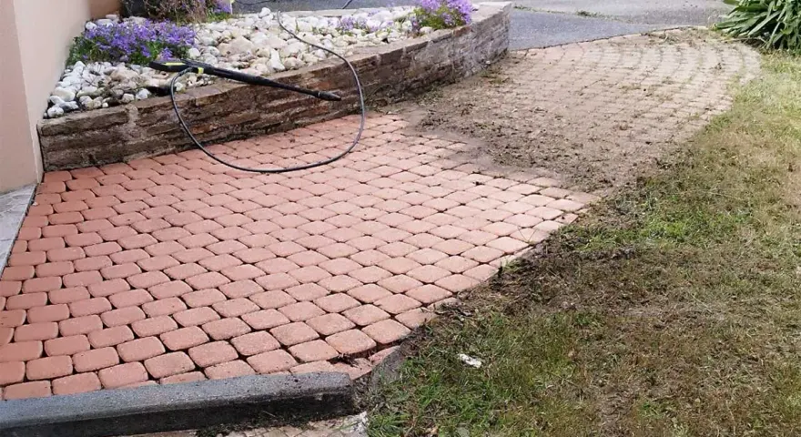 Un nettoyeur haute pression enlève les taches noires, lichen noir sur pierre. Le pavage est presque propre.