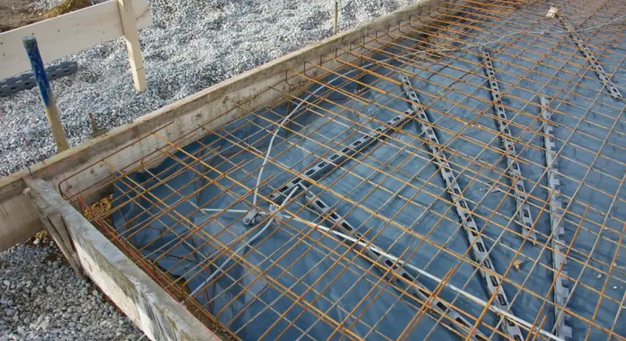 Préparation pour couler une dalle béton : film plastique, treillis métallique et coffrage en bois. On ne coule pas une dalle béton directement sur la terre.