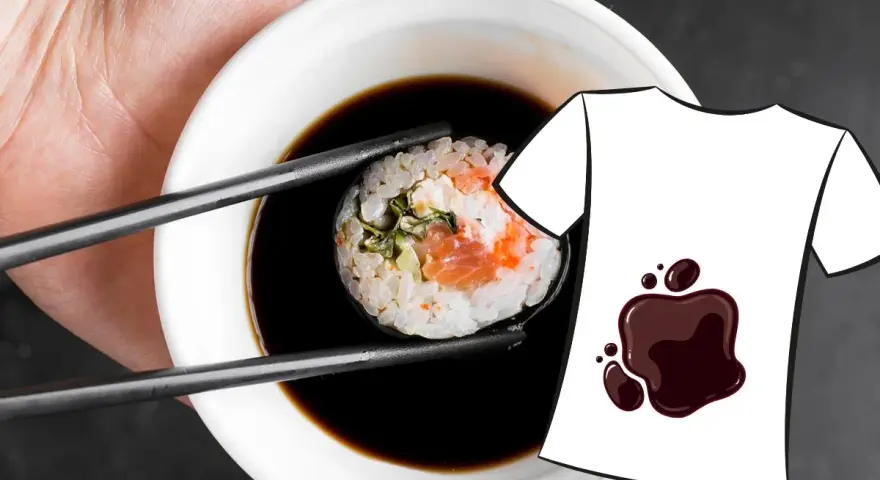 Une main tient une pince à sushi trempant un rouleau dans une sauce soja. Une tache de sauce soja est dessinée sur un t-shirt blanc.