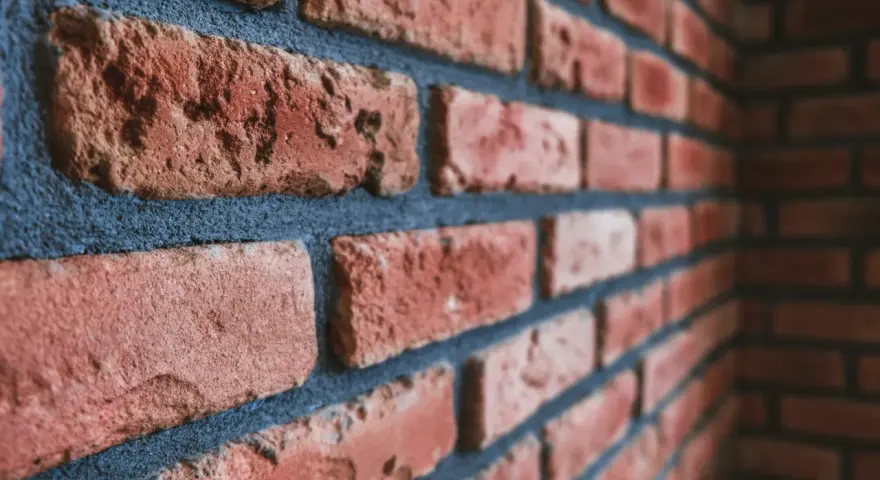 Gros plan sur un mur de briques rouges avec des joints bleus foncés. Idéal pour illustrer comment nettoyer des briques après avoir fait les joints.
