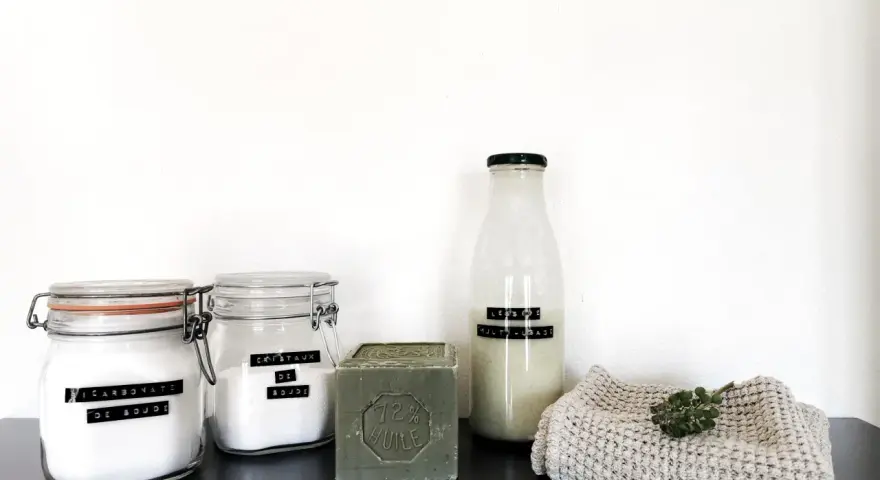 Ingrédients pour la meilleure recette lessive maison : bicarbonate de soude, cristaux de soude, savon de Marseille et une bouteille de lessive liquide.