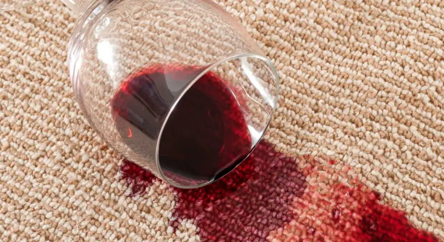 Verre de vin renversé sur la moquette, créant une tache rouge. Une astuce de grand-mère pour une tache de vin rouge serait utile ici.