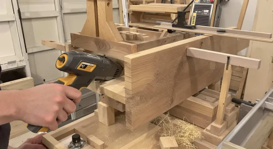 Un artisan utilise un outil pour enlever le saturateur bois d'une pièce de bois massif.