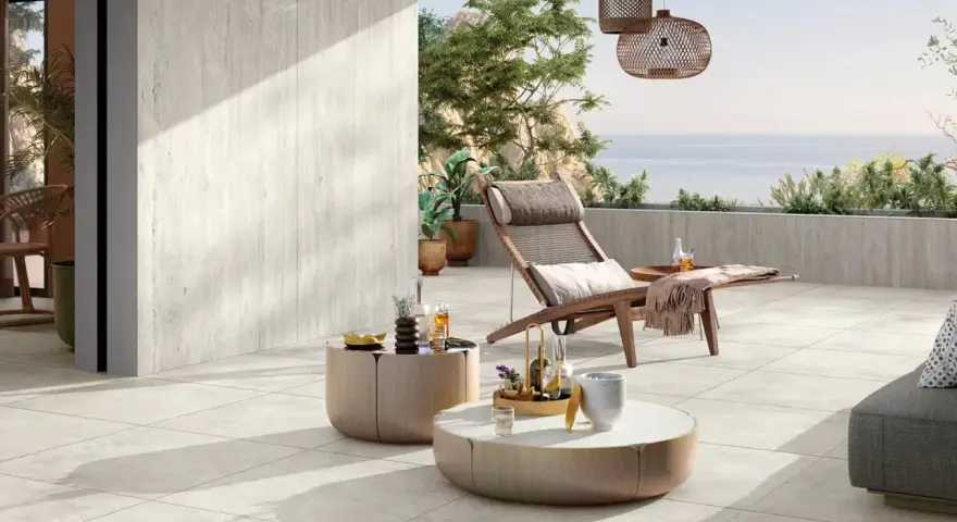 Terrasse avec pose travertin sur carrelage existant. Chaise longue, tables basses et vue mer. Ambiance détente.