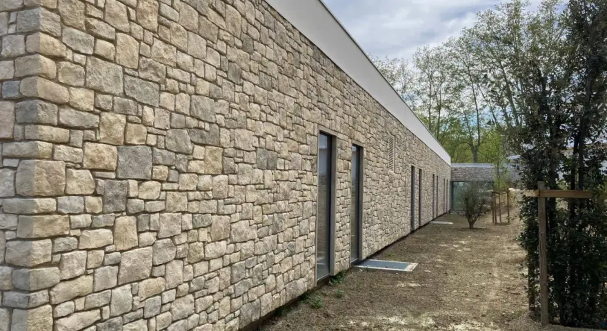 Façade d'un bâtiment moderne avec un revêtement en pierre calcaire construction, créant une esthétique naturelle et robuste.