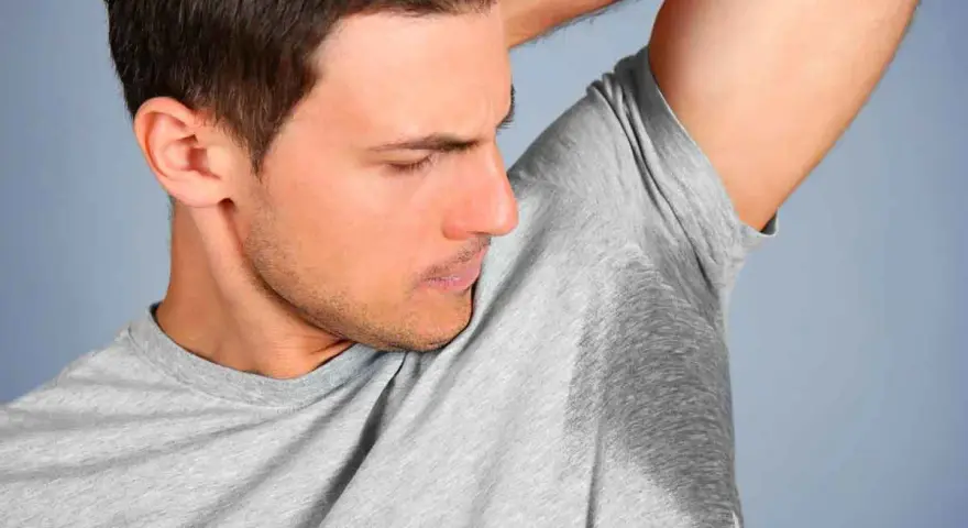 Un homme sent ses aisselles moites, cherchant comment enlever les taches sous les aisselles.