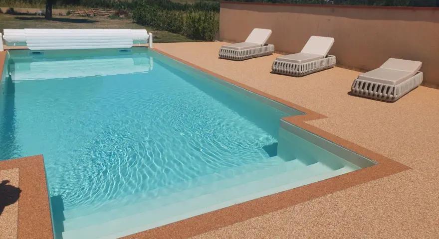 Piscine avec escalier, entourée de **pierre autour piscine** et de chaises longues.