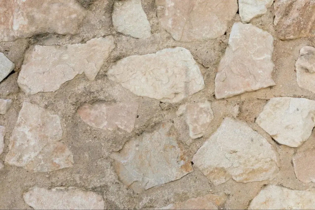 Mur en pierres naturelles irr&eacute;guli&egrave;res, avec des variations de couleurs allant du beige ros&eacute; au gris. Id&eacute;al pour apprendre comment enlever des taches sur de la pierre naturelle.