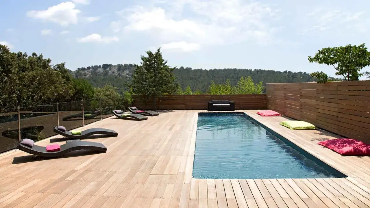 Terrasse en bois avec piscine, chaises longues et coussins color&eacute;s. Un cadre id&eacute;al pour l'entretien piscine bois et la d&eacute;tente.