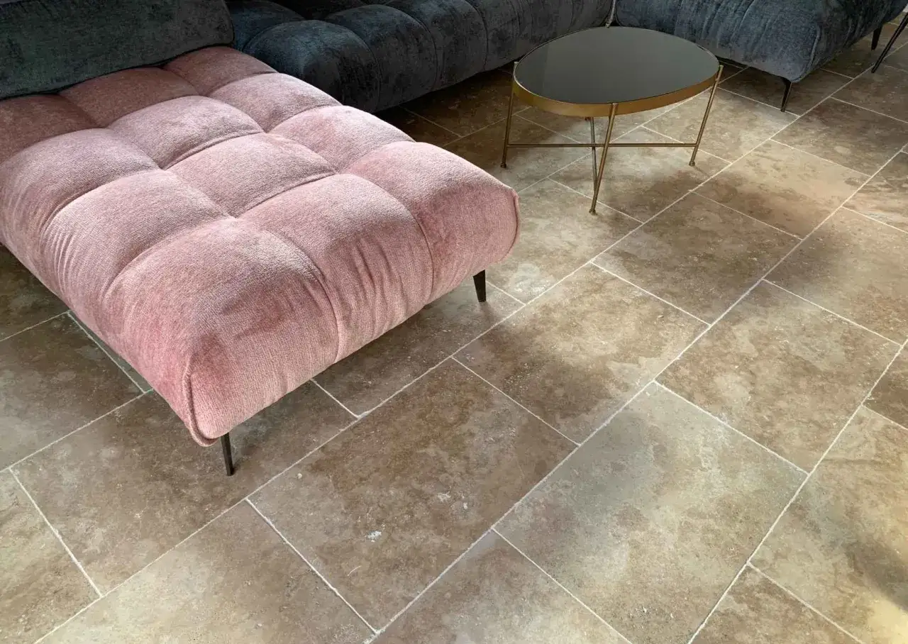 Un canap&eacute; rose et un fauteuil gris sur un sol en pierre naturelle. Le traitement pierre met en valeur la beaut&eacute; authentique des dalles.