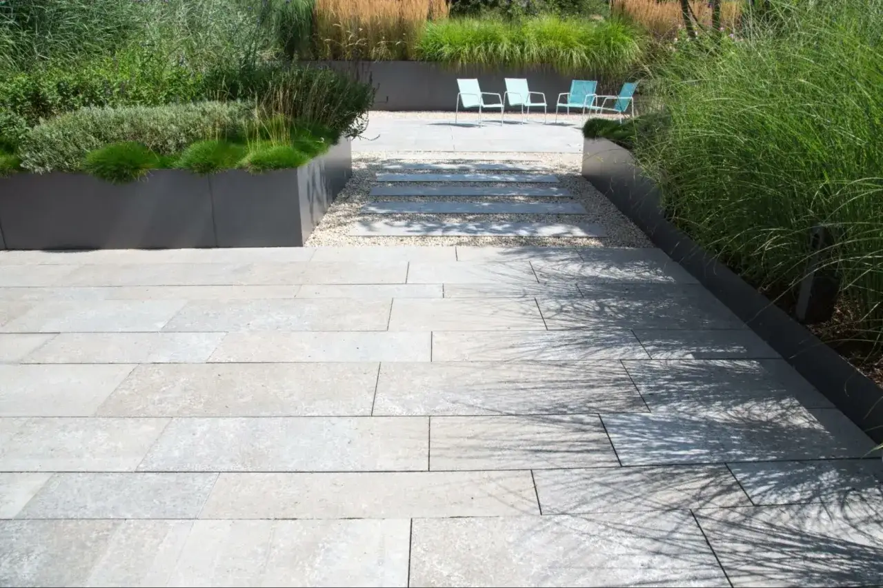 Terrasse moderne avec dalles de pierre claire. Les inconvénients de la pierre reconstituée, comme la porosité, peuvent être visibles sur ce type de revêtement.