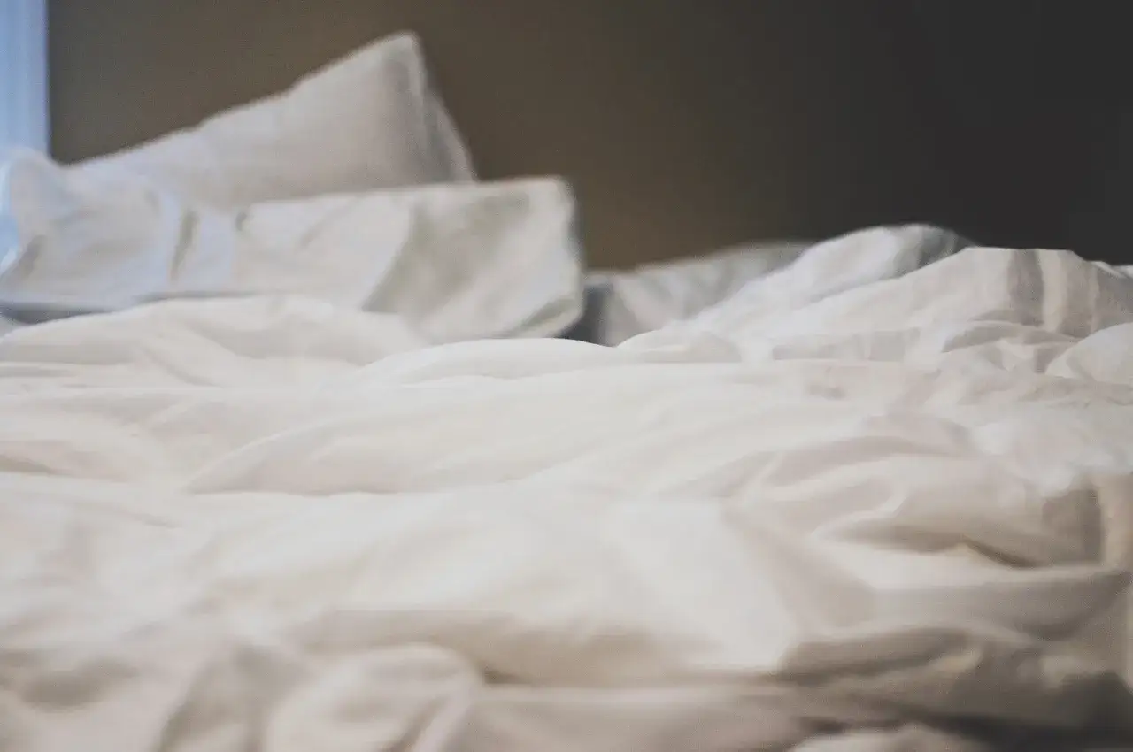 Linge blanc ancien froiss&eacute;, avec quelques taches jaunes discr&egrave;tes. Un lit d&eacute;fait, pr&ecirc;t pour de nouveaux r&ecirc;ves.