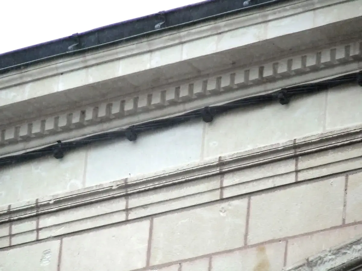 Détails architecturaux en pierre de tuffeau, montrant des câbles noirs fixés. Un aperçu de comment restaurer la pierre de tuffeau.