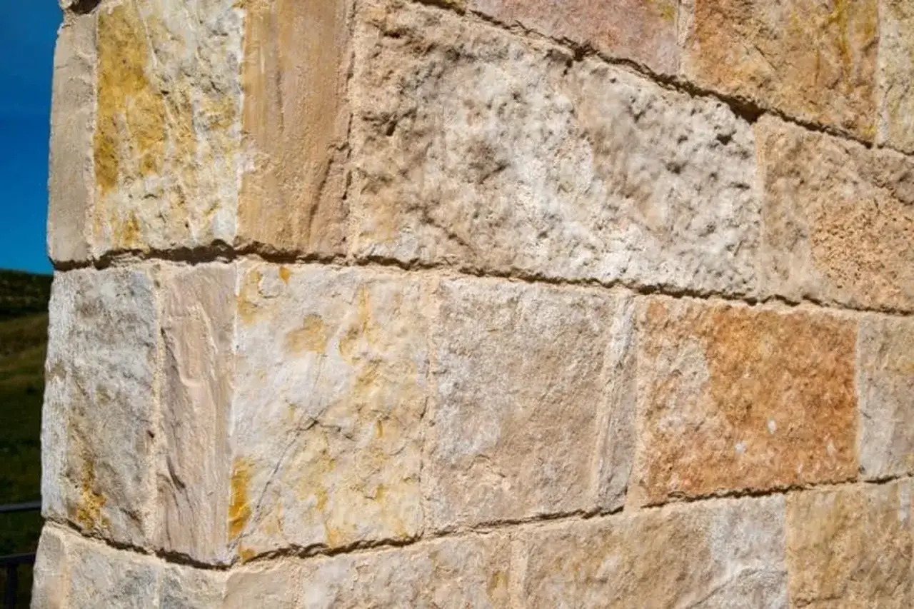 Gros plan sur un mur en pierre de construction, montrant divers types de pierres aux teintes beiges et ocres, avec des textures variées.