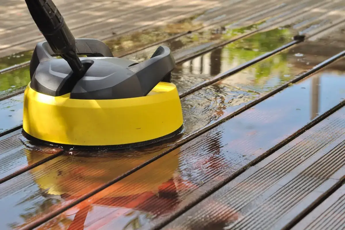 Nettoyeur haute pression jaune sur une terrasse en bois mouillée, montrant comment enlever le vert sur du bois.