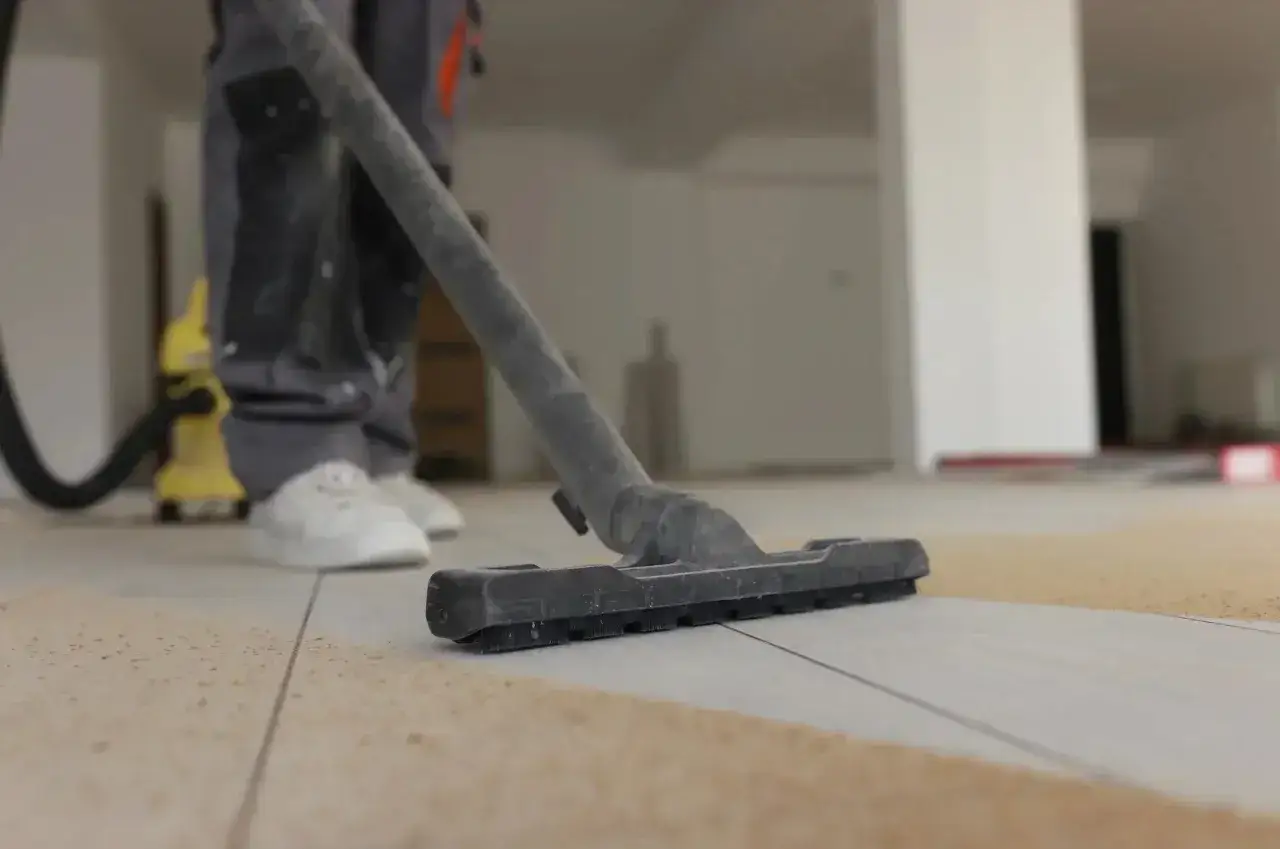 Un aspirateur en action pour enlever l'enduit sur le carrelage. Le travail de nettoyage commence.