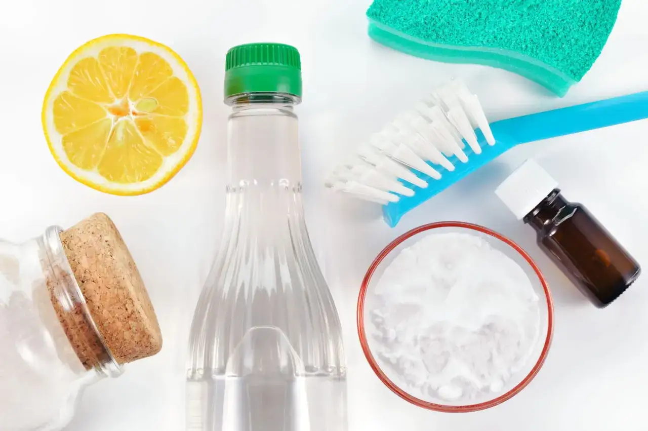 Citron, bicarbonate de soude, éponge, brosse et bouteille de vinaigre blanc pour un nettoyage écologique.