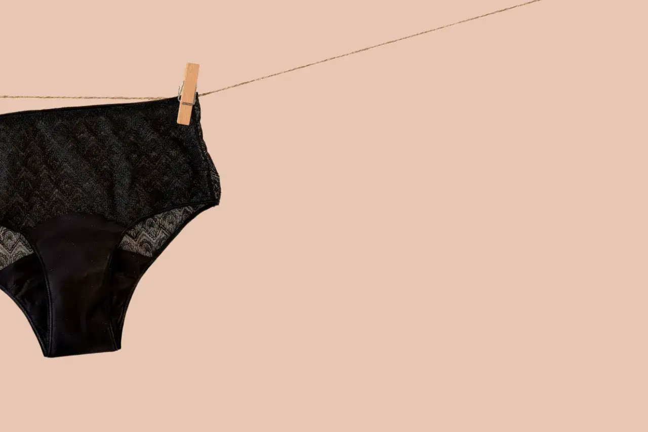 Culotte menstruelle noire en dentelle, suspendue sur une cordelette. Un guide simple pour savoir comment laver culotte menstruelle.