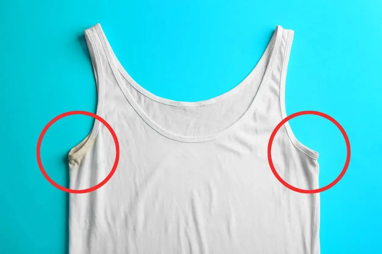 Débardeur blanc avec une tache de transpiration incrustée sous le bras gauche, mise en évidence par un cercle rouge.