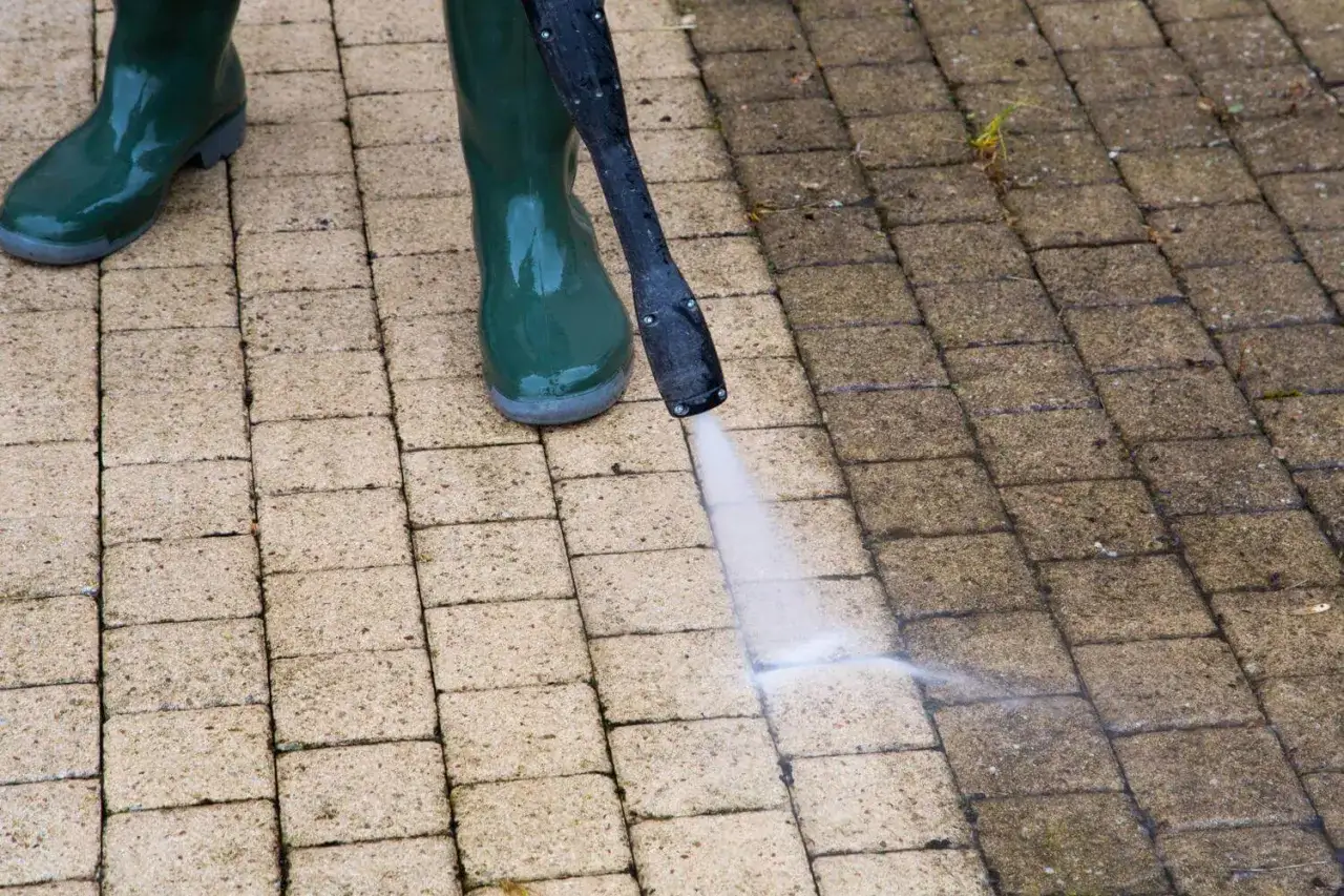 Nettoyer pavé autobloquant vinaigre blanc : un jet d'eau nettoie la moitié d'une allée pavée, révélant la différence.