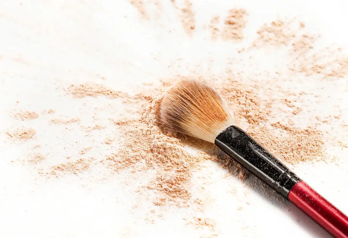 Poudre libre &eacute;parpill&eacute;e autour d'un pinceau de maquillage. Apprenez comment enlever une tache de fond de teint avec ces astuces.