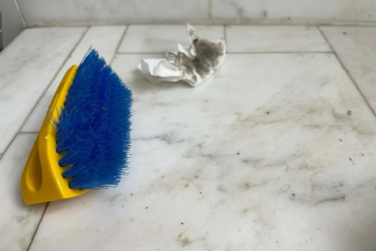 Brosse bleue et jaune pr&ecirc;te &agrave; nettoyer sol carrelage tr&egrave;s sale. Un mouchoir plein de poussi&egrave;re est &agrave; c&ocirc;t&eacute;.